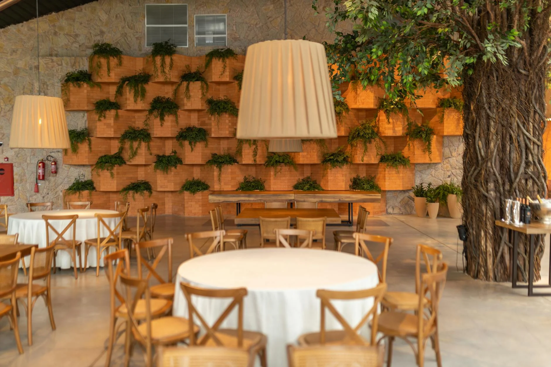 Stylish restaurant interior featuring wooden furniture and lush green plant wall. — Foto: Matheus Bertelli / Pexels